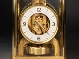 a gold clock with a white face on a black background