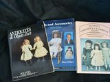 three books of antique dolls and accessories on a black cloth