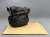a black leather purse sitting on top of a tan cloth