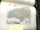 un livre ouvert, sur lequel figure une carte, posé sur une table