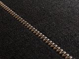 close up of a zipper on a black shirt with a gold zipper