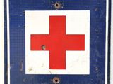 blue and white sign with a red cross on it on a white wall