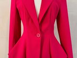 La veste est rose et possède un col « pepo ».