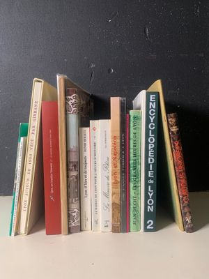 Plusieurs livres sont alignés sur une étagère devant un mur noir
