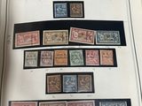 un livre ouvert sur lequel sont collés plusieurs timbres