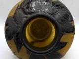 a black and yellow vase with leaves on it