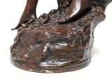 a bronze statue of a woman sitting on a rock