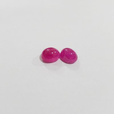 a pair of pink gems on a white surface