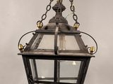 une lanterne à l'ancienne suspendue à une chaîne sur un mur blanc