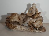 une statue représentant un homme assis sur un rocher avec un chien