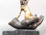 statue en bronze représentant une femme assise sur un rocher, posée sur un socle en marbre