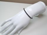 a white mannequin hand with a black beaded bracelet
