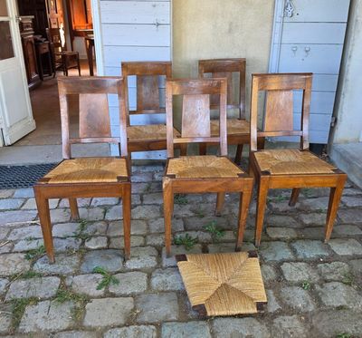 quatre chaises en bois posées sur un sol pavé, devant une porte