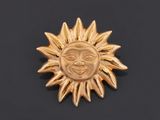 a close up of a gold sun broochle on a black surface