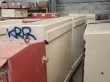 de nombreux réfrigérateurs blancs recouverts de graffitis dans un entrepôt