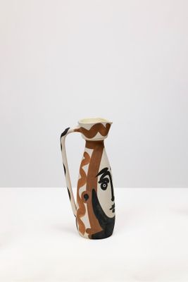 une image représentant un vase orné d'un visage, posé sur une table