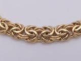 a gold chain link necklace with a clasp on a white background