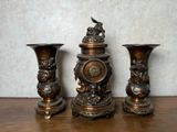 trois vases en bronze posés sur une table en bois