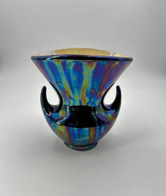un vase en verre coloré avec une poignée noire sur fond blanc