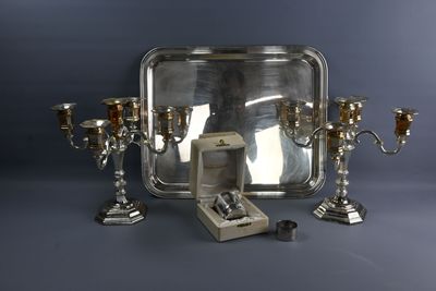 un plateau en argent sur lequel se trouvent trois bougies en argent et une bague