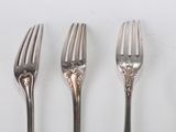 three forks and a knife on a table with a white background