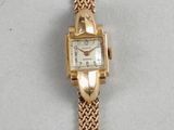 an image of a gold wrist watch with a mother of pearl dial