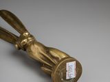 an antique brass rabbit bottle opener on a white surface