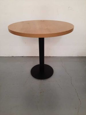 a round wooden table with a black metal base