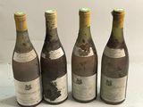 quatre bouteilles de vin sont alignées sur une surface blanche
