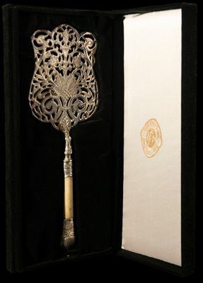 une cuillère en argent finement ouvragée, avec un manche en bois, présentée dans un coffret noir
