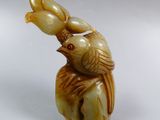a small statue of a bird sitting on top of a piece of wood