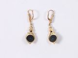 a pair of gold and black stone earrings on a white background