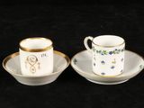 two cups and saucers sitting on a black surface