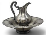 a silver pitcher on a silver plate on a white background