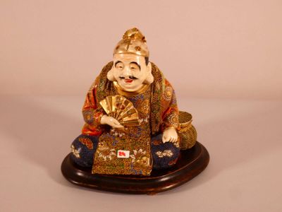 a figurine of a smiling buddha holding a fan