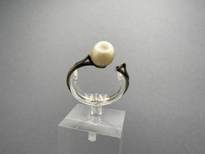 a ring with a pearl on top of a clear stand
