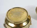 two gold pots sitting next to each other on a white surface