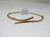 gros plan d'un bracelet en or sur une surface blanche