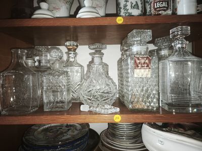 many glass jars and plates on a shelf in the kitchen