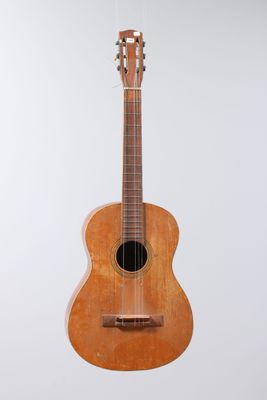 a small wooden guitar hanging from a white wall