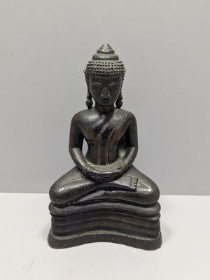 statue of a person sitting in a meditation position on a white surface