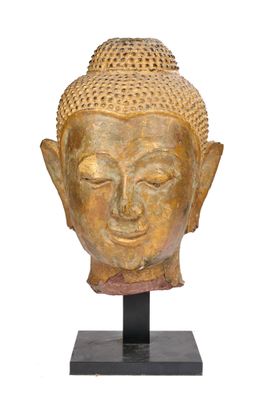 une image représentant une tête de Bouddha dorée posée sur un socle noir