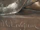 a bronze statue of a person laying down on a book