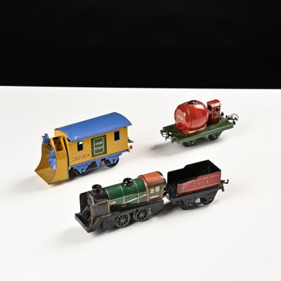 trois petits trains miniatures posés sur une surface blanche, sur fond noir