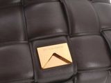 the hand of a person is holding a brown bag with a gold button