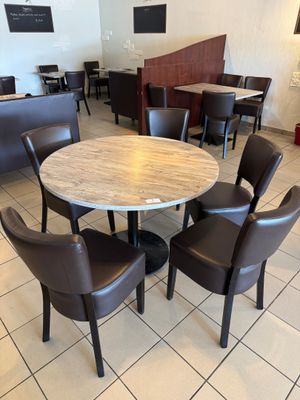 tables and chairs are arranged around a round table in a restaurant