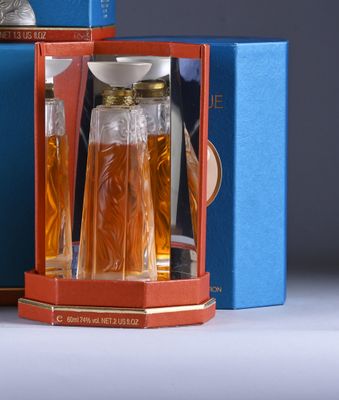 a bottle of perfume in a blue box next to a blue box with a clock on it