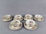 six tasses et soucoupes ornées de motifs floraux, posées sur une table