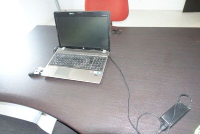 un ordinateur portable posé sur un bureau, avec son chargeur