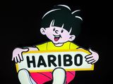 une photo d'une petite fille tenant une pancarte sur laquelle on peut lire « Haribo »